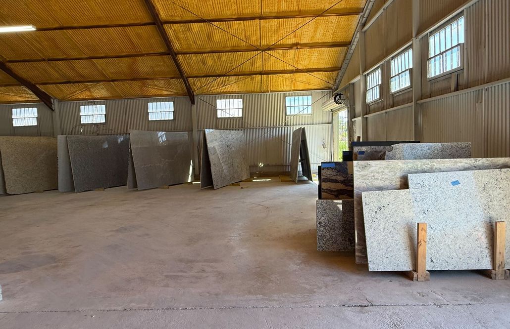 Empty warehouse interior with stacked stone slabs and a yellow roof