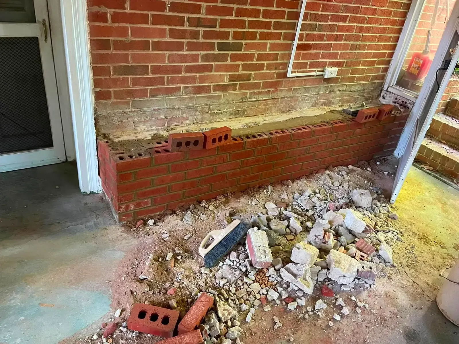 Brick wall under construction with rubble and broken bricks piled along the floor indoors