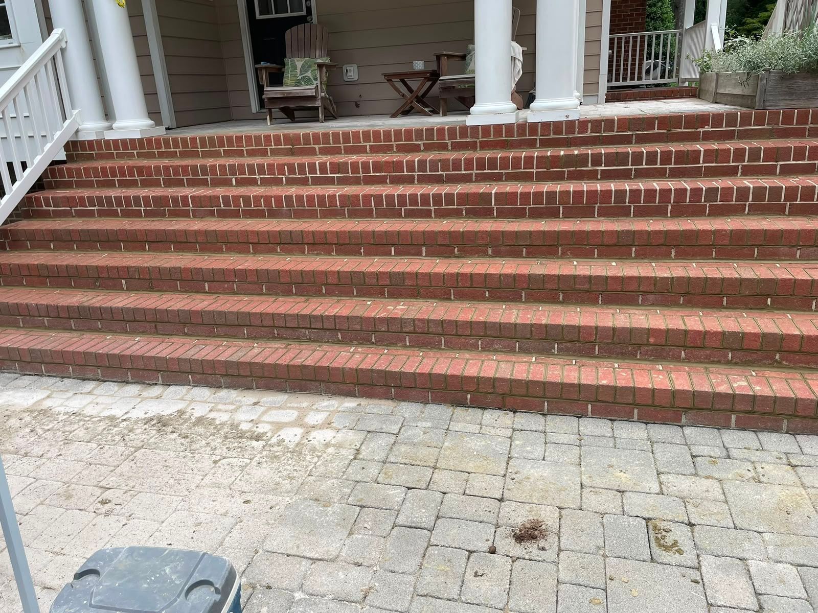 Brick front steps leading to a porch with white columns and a paved walkway in front