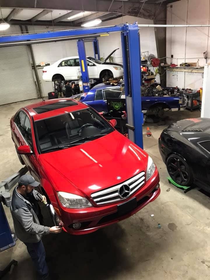 mechanic working on red Mercedes in an auto repair shop