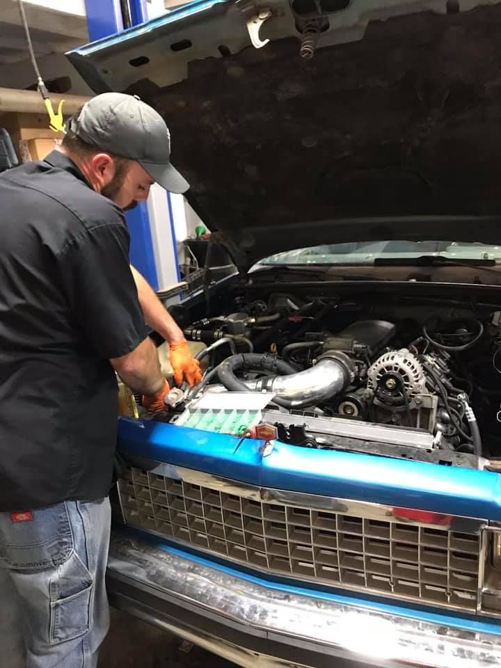 mechanic works on a blue car engine
