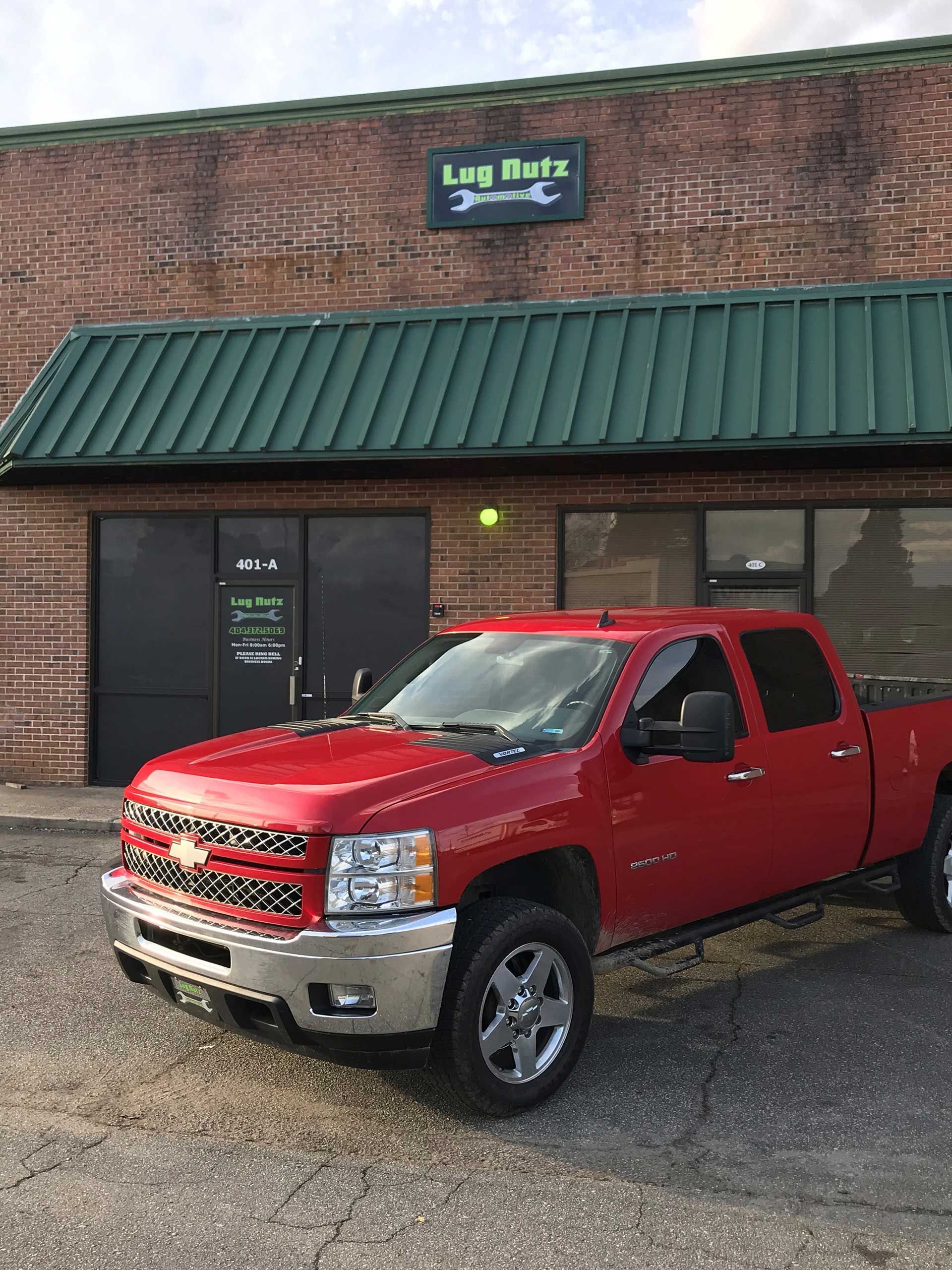 a red Chevy pickup truck parked in front of a brick building