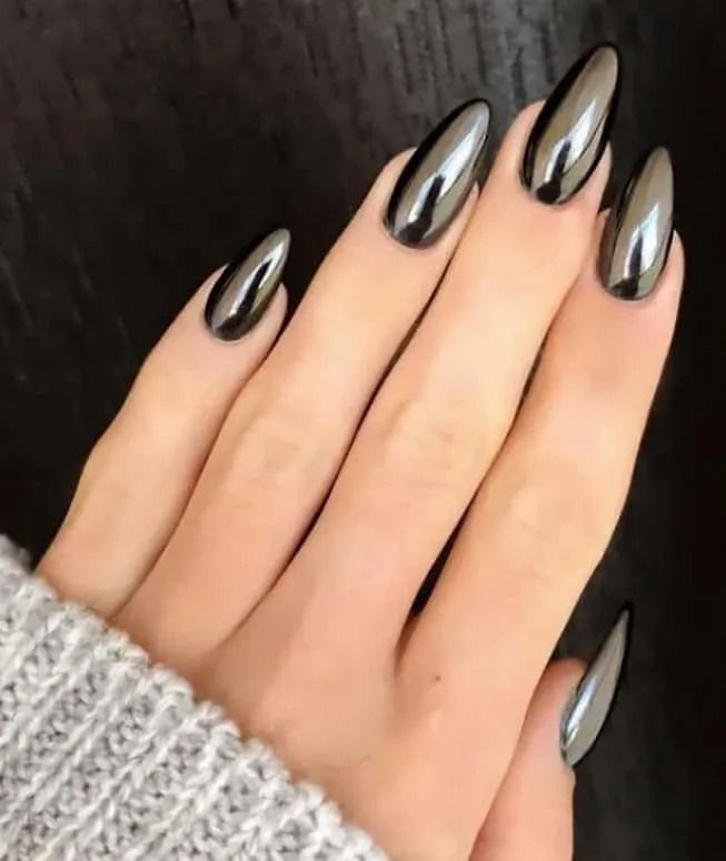 Hand with long, glossy, metallic charcoal-colored almond-shaped nails.