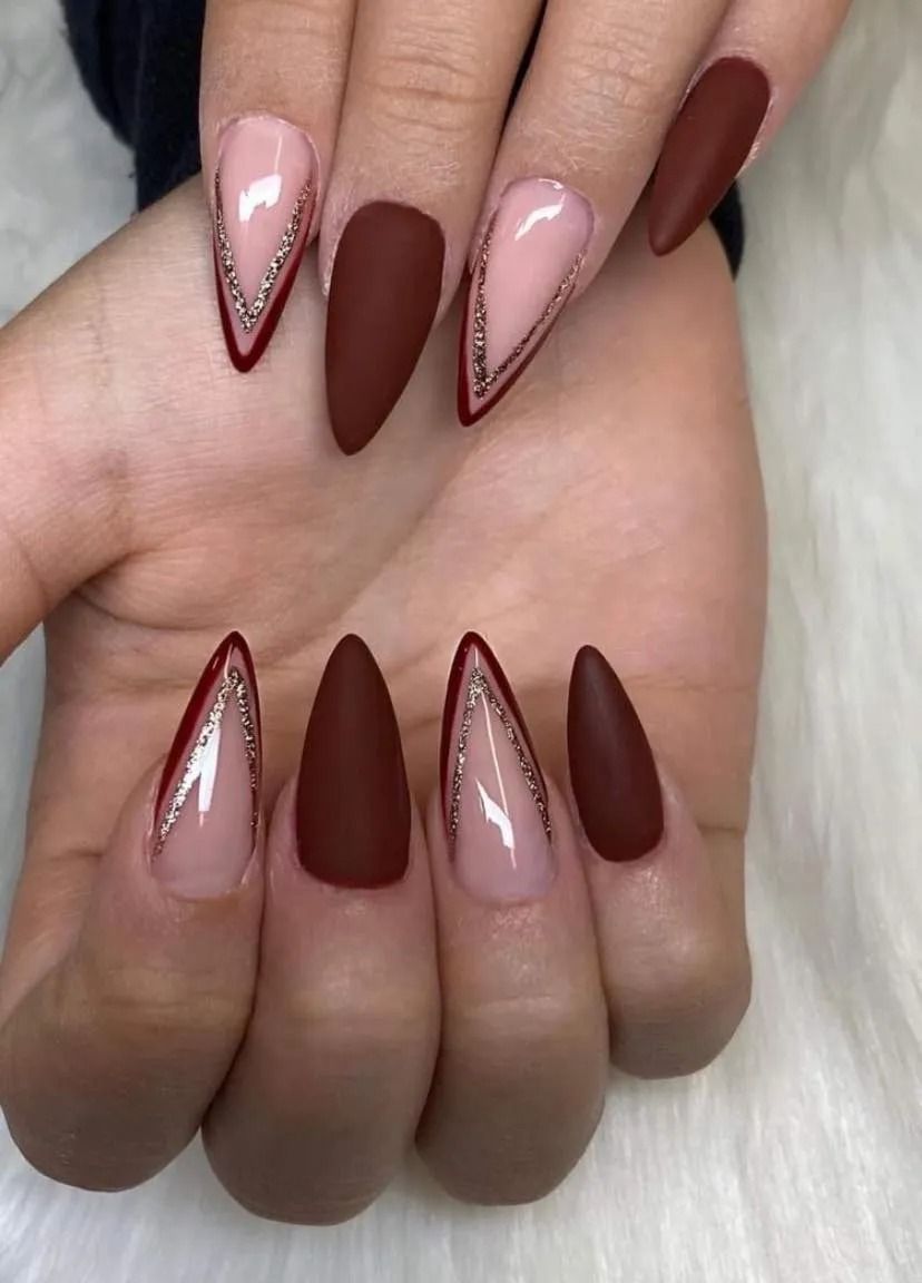 Hand with almond-shaped nails in matte brown and nude with silver glitter accents.