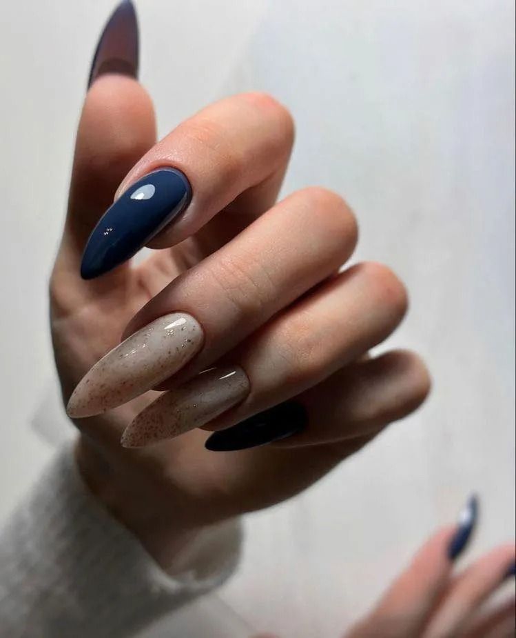 Hand with long, pointed nails; some blue, some speckled beige.