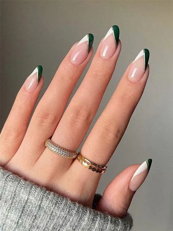 Hand with long, almond-shaped nails. Green and white french tips. Two gold rings.