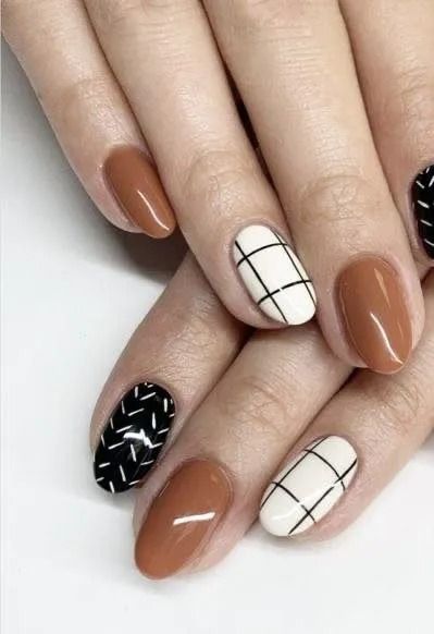 Hands with oval-shaped nails, painted in brown, white plaid, and black geometric patterns.