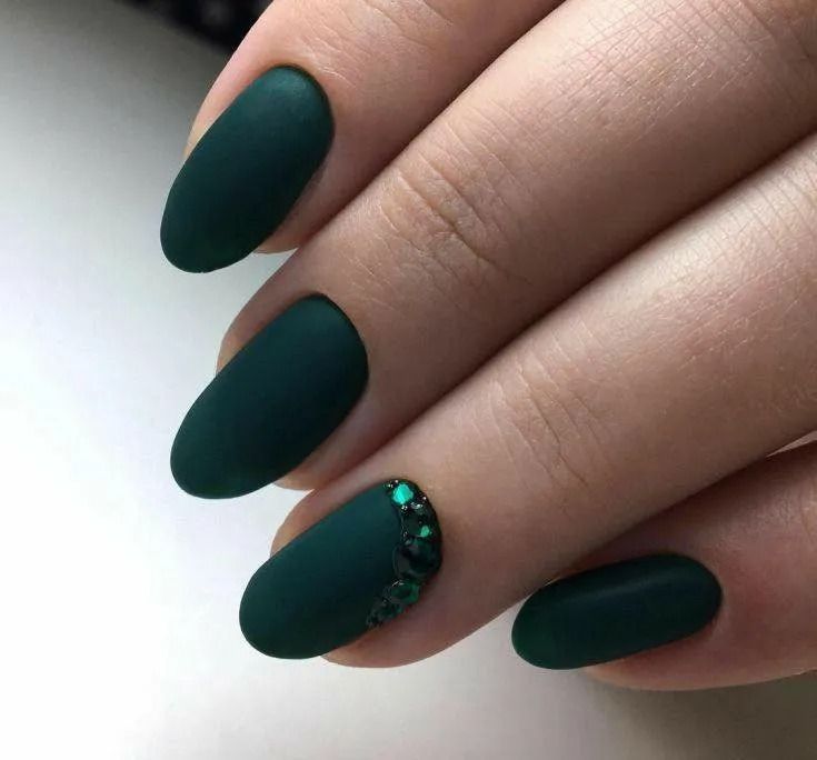 Dark green matte oval-shaped nails, one with emerald glitter accent.