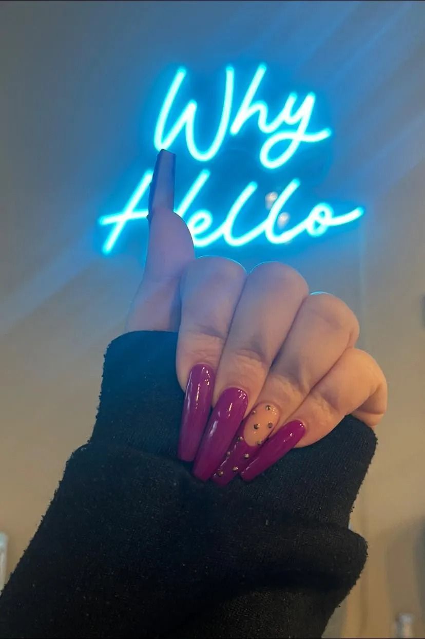 Hand with long, dark pink nails pointing towards a 