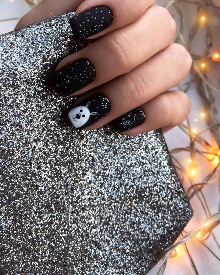 Black matte nails with silver flecks and a white bunny design.