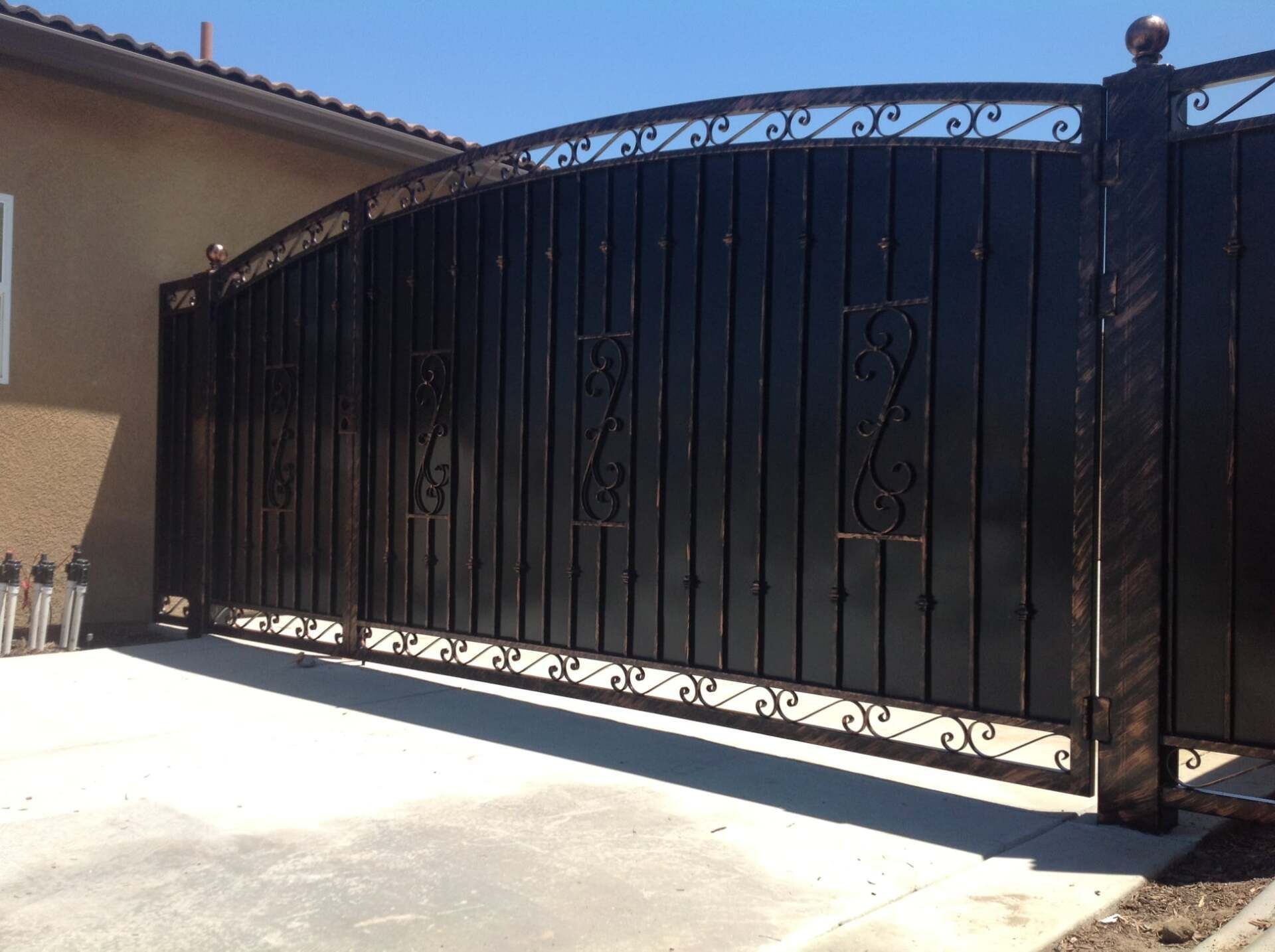 Black metal driveway gate with ornate scrollwork.