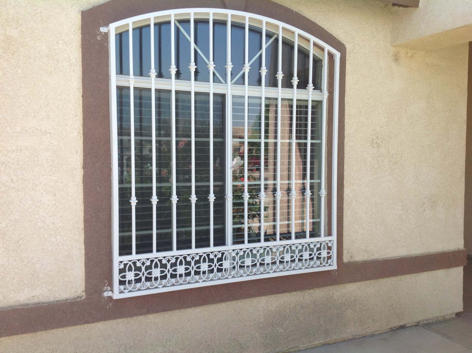 White barred window on a beige stucco wall, brown trim.