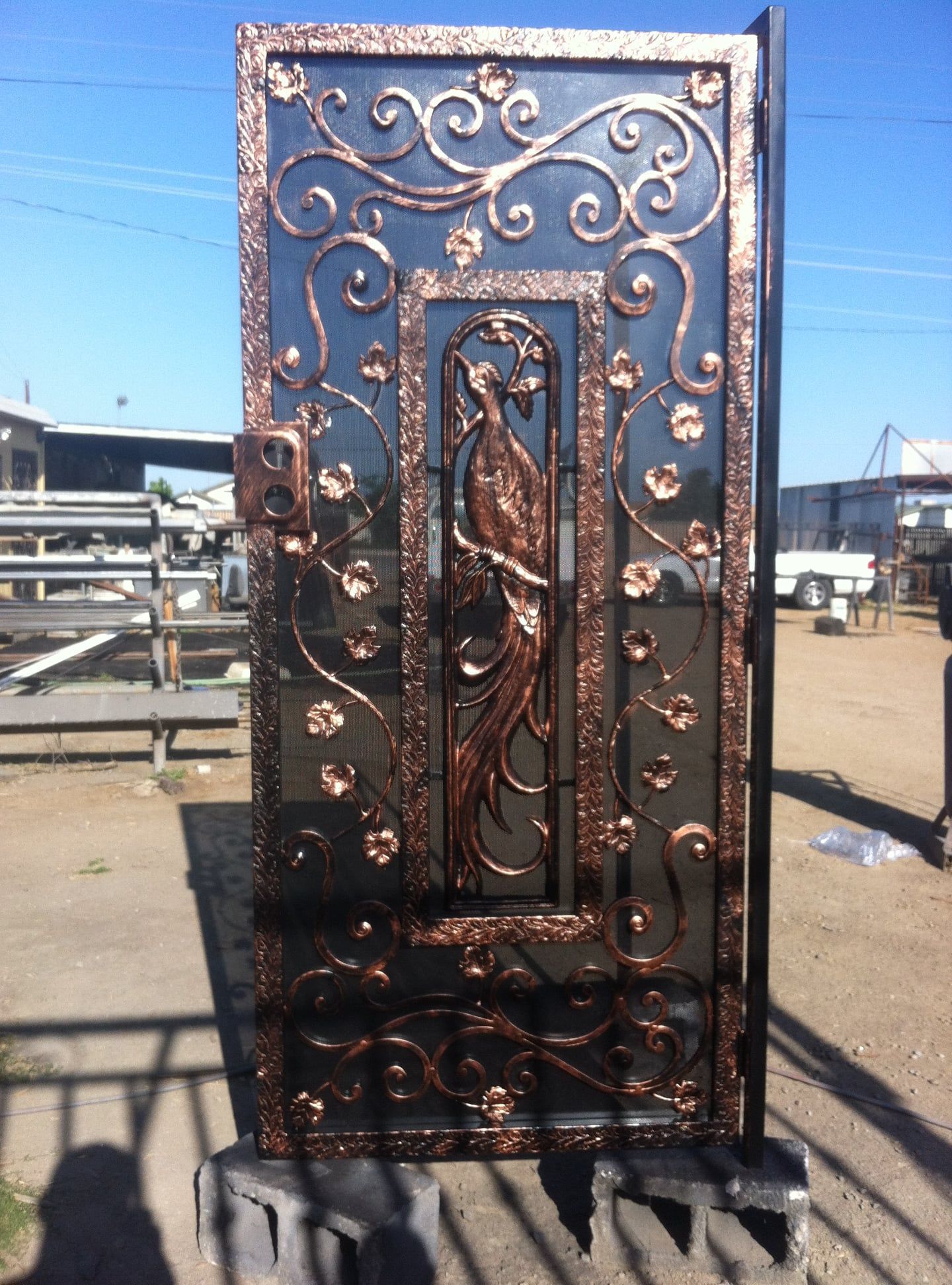 Ornate wrought iron gate with copper accents, featuring a phoenix design.
