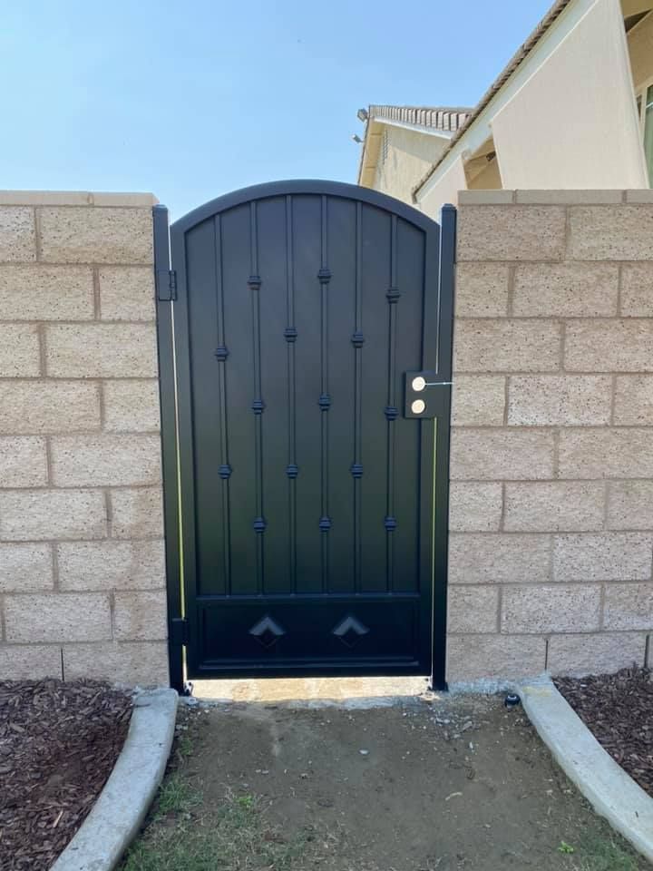 Black metal gate set between two brick walls.