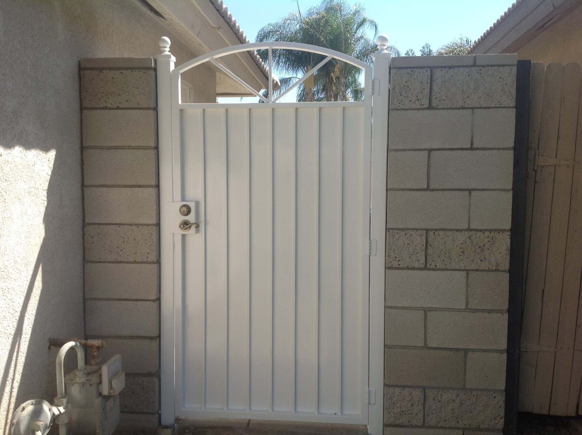 White gate set between concrete block walls.