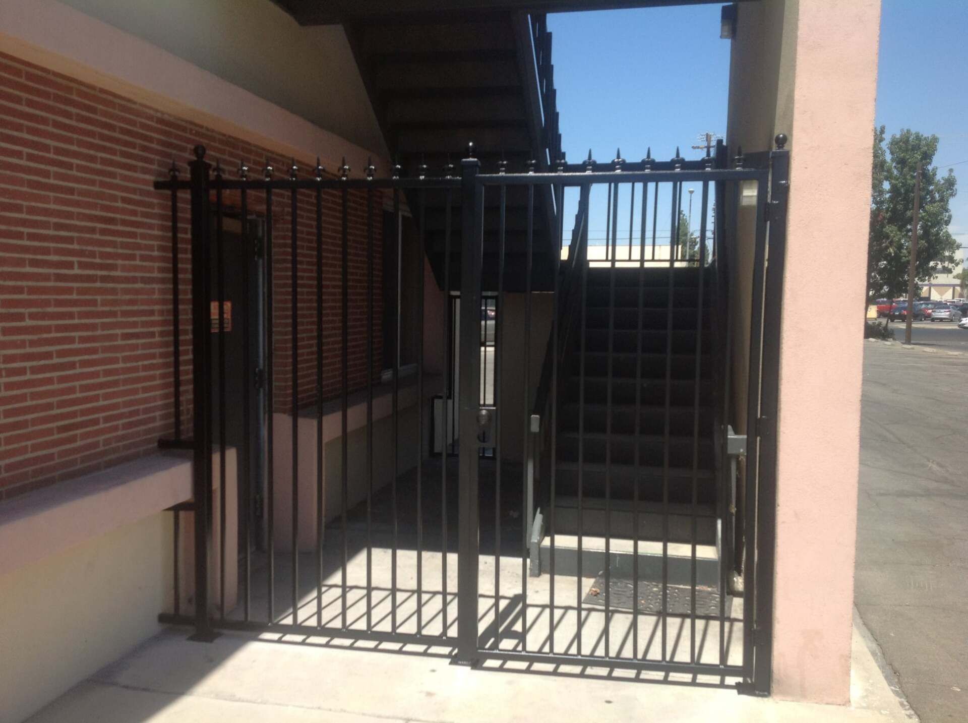 Black metal security gate blocks access to stairs and a doorway.