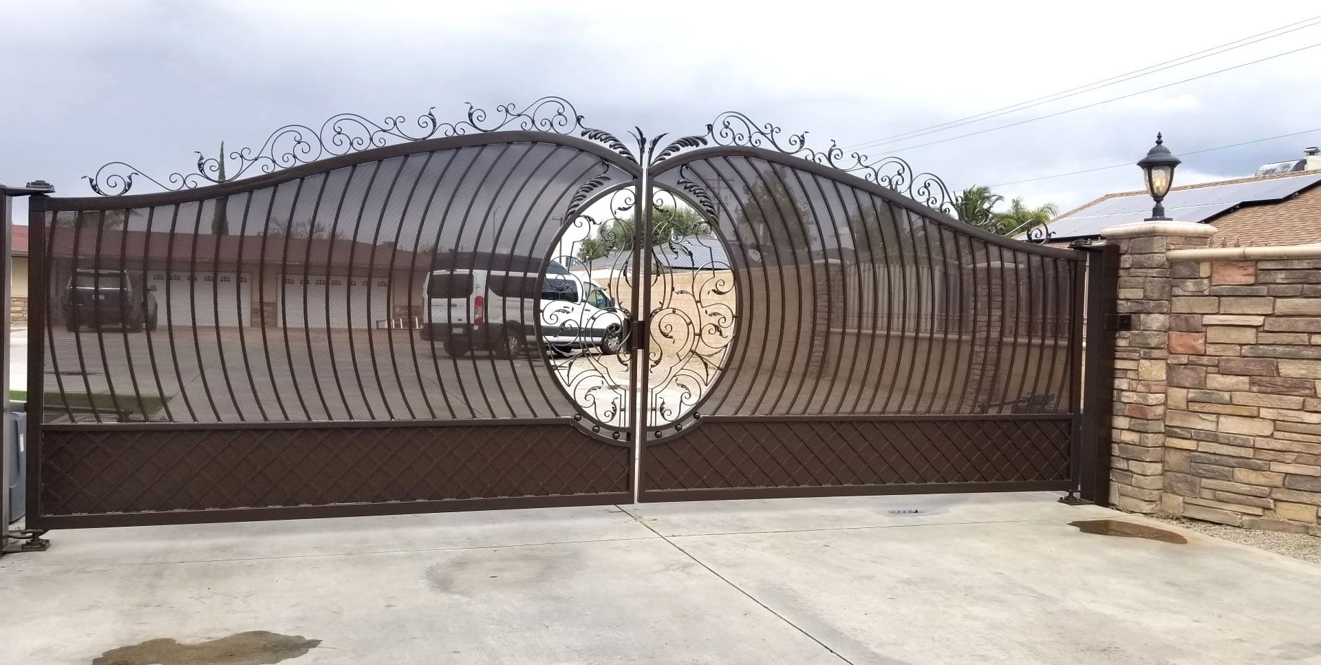 Ornate metal gate with a circular design, leading to a property.