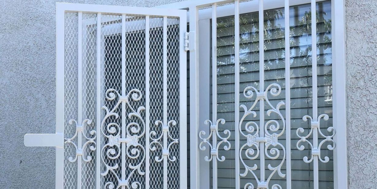 White security door with decorative scrollwork on a textured wall.