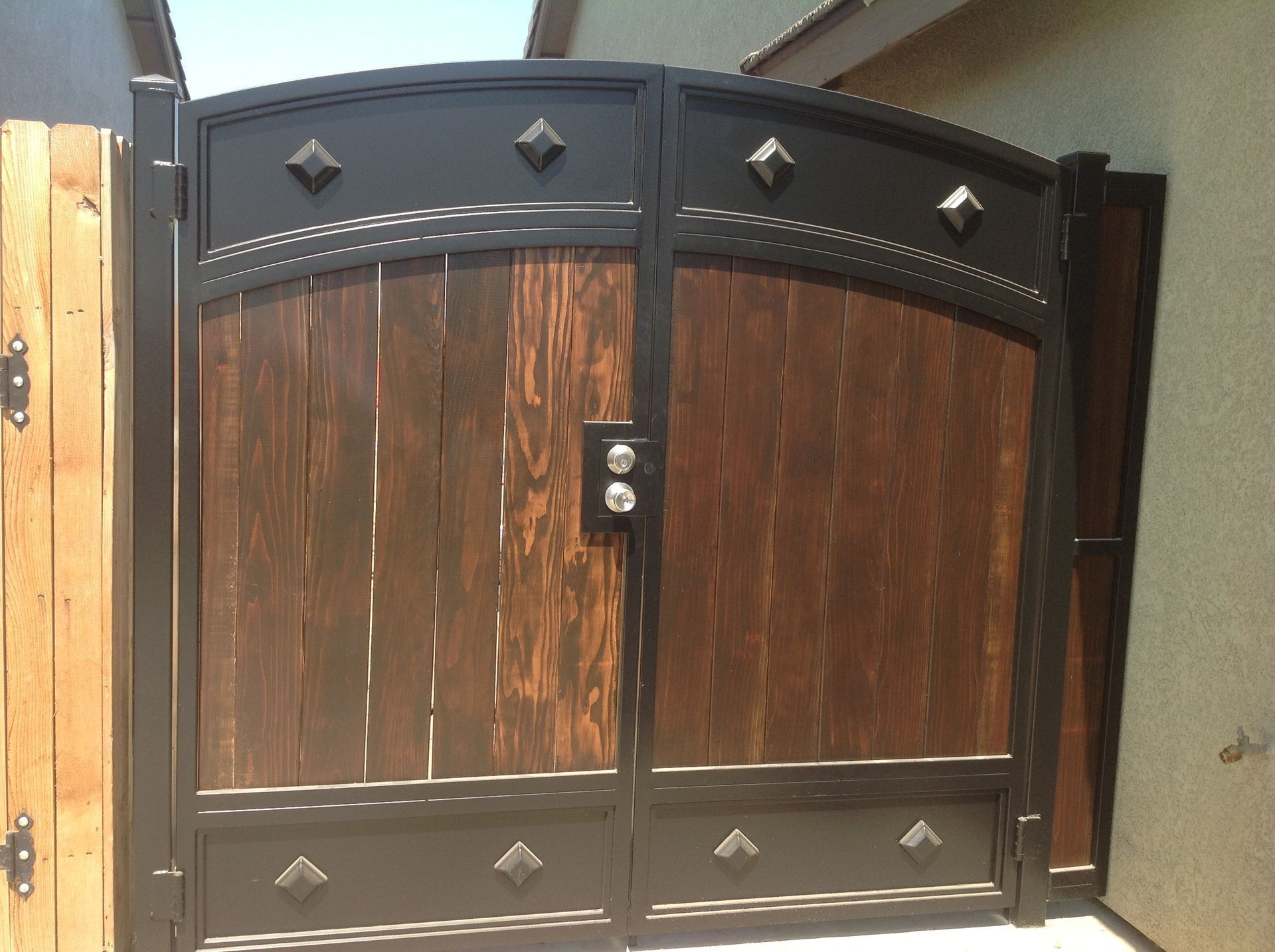 Two wooden gates with black metal frame and decorative accents.