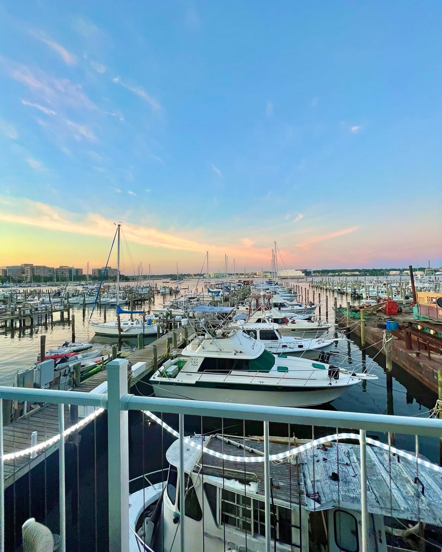 Boats docked at a marina under a colorful sunset sky.
