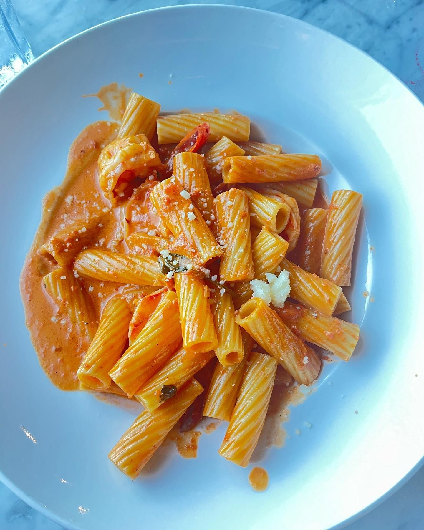 Rigatoni pasta with creamy orange sauce in a white bowl.
