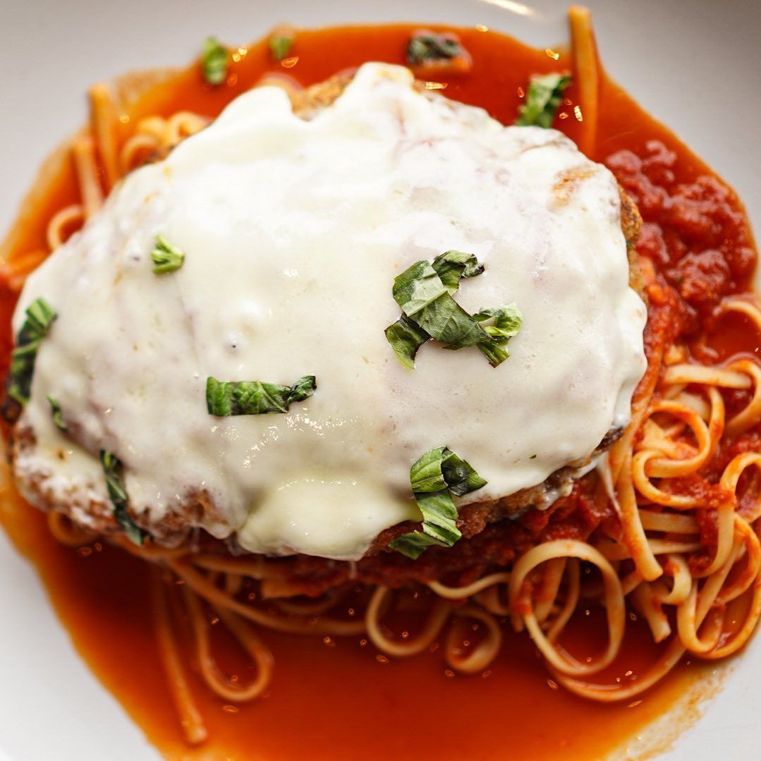 Chicken Parmesan with tomato sauce, mozzarella, and basil over pasta.