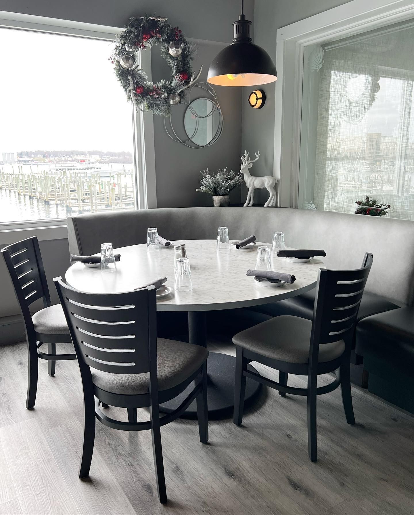 Restaurant dining table with four chairs, a booth, and a window overlooking a body of water.