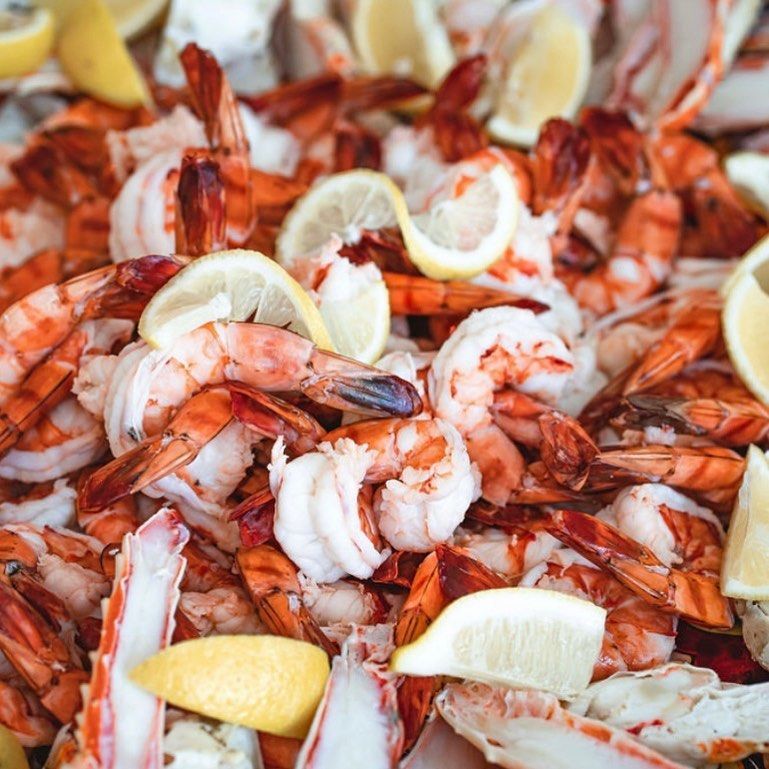 Shrimp and lemon slices on a platter with crab legs.