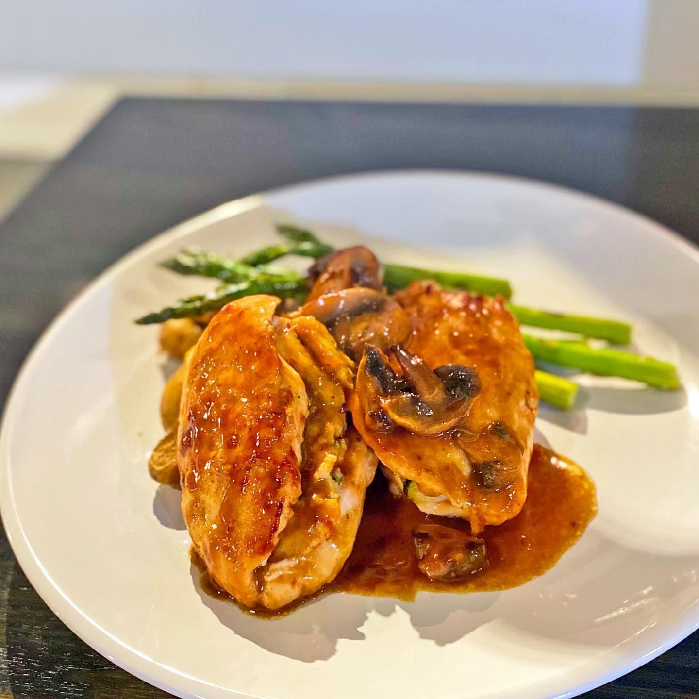 Chicken breast dish with mushrooms and asparagus on a white plate.