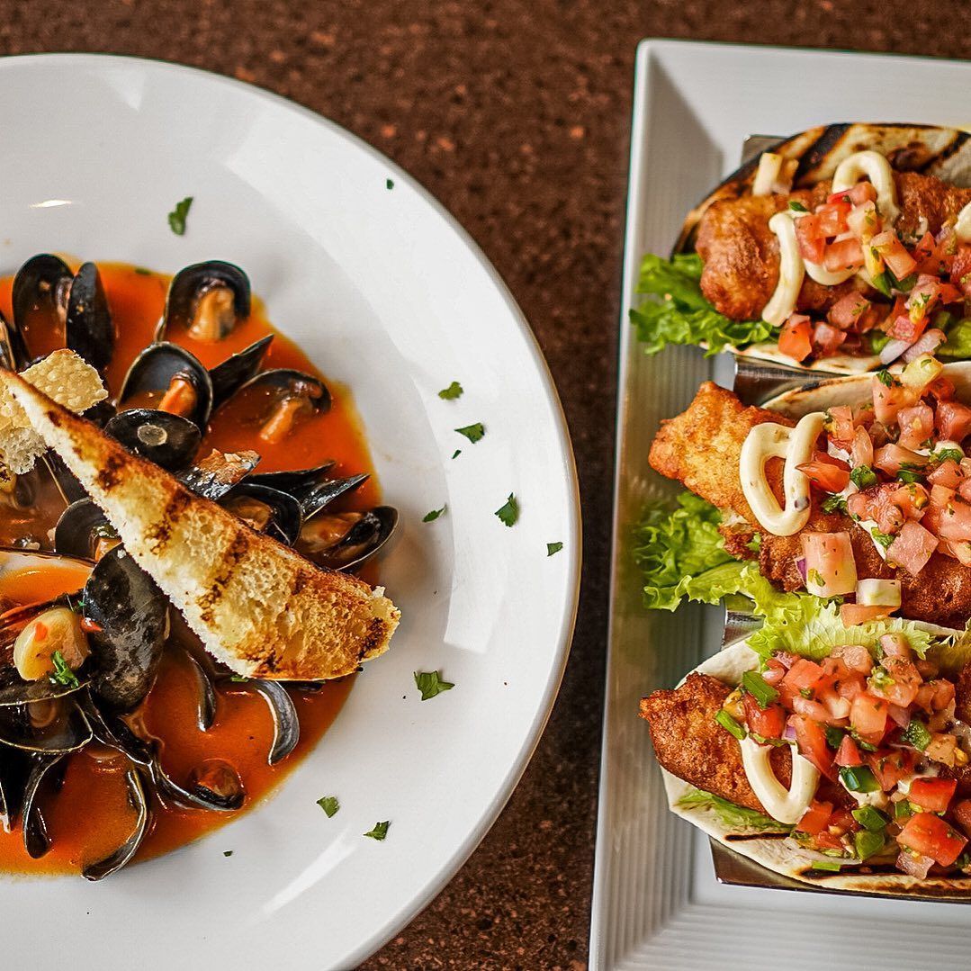 Plate of mussels in tomato sauce with grilled bread, fish tacos with salsa.