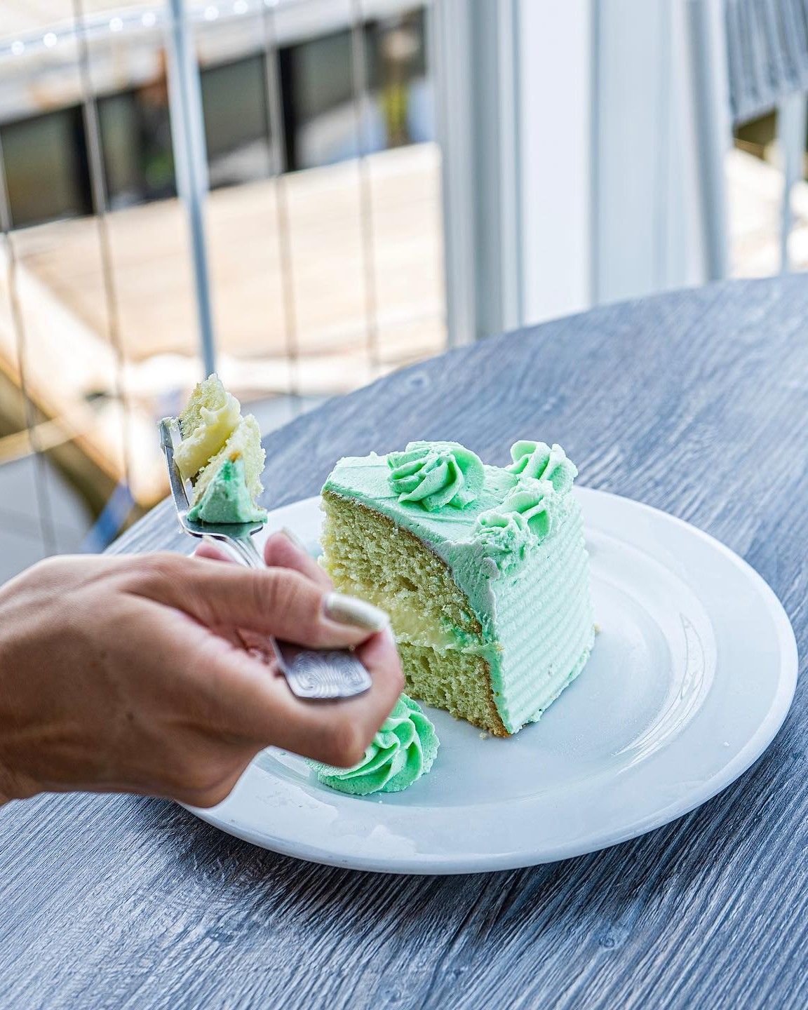 Slice of cake with mint green frosting on a white plate.