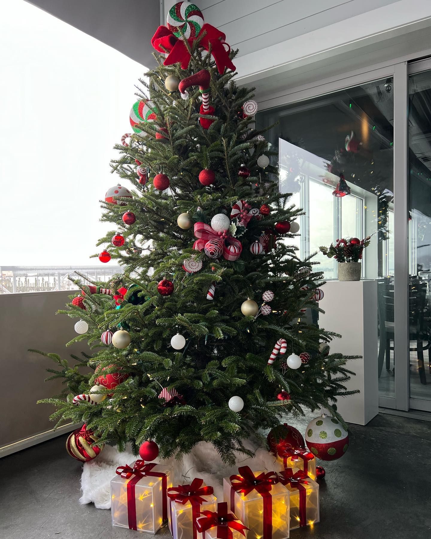 Christmas tree decorated with red, white, and gold ornaments, candy canes, and gift boxes.