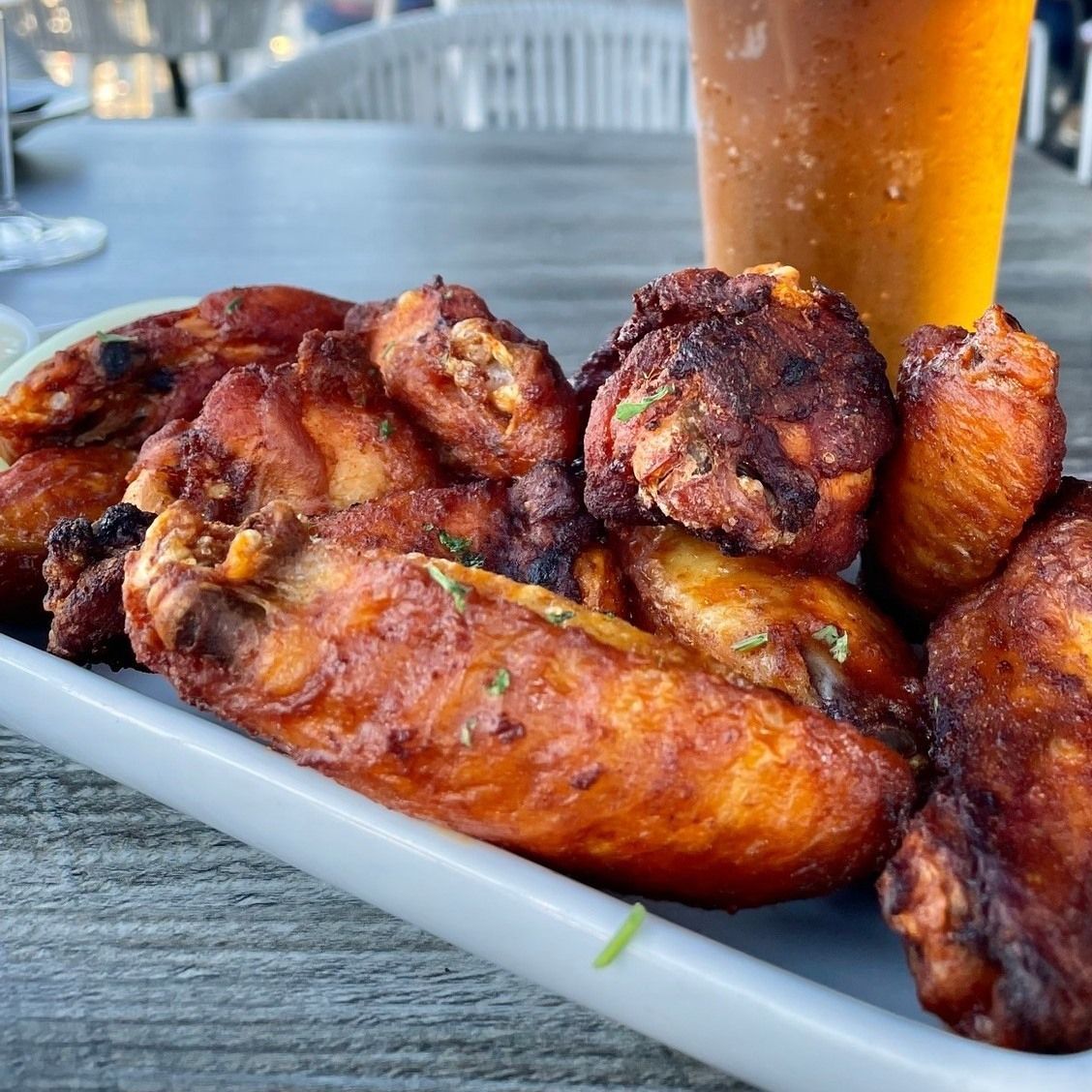 Plate of fried chicken wings with a glass of beer on a table.