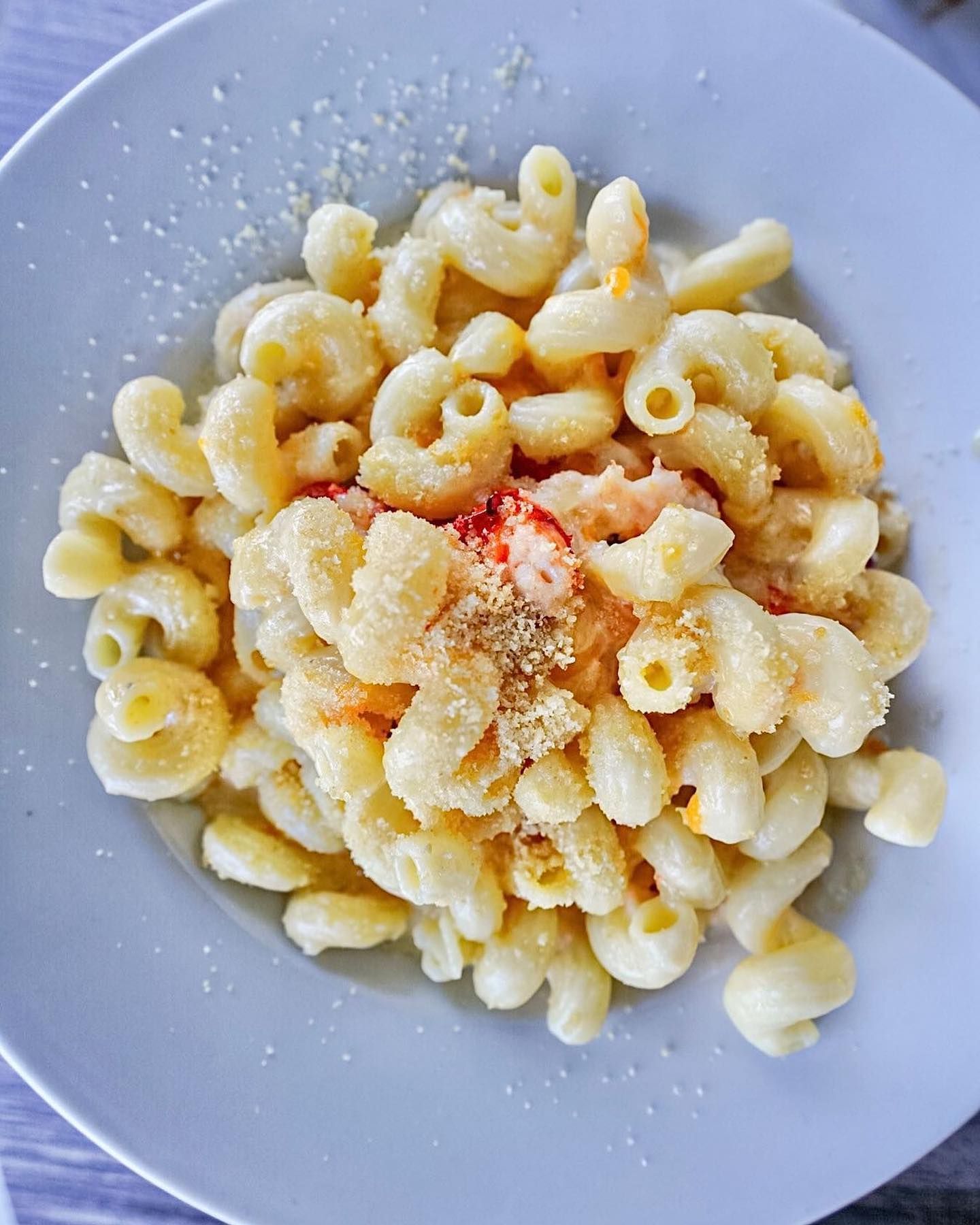 Macaroni and cheese on a light blue plate, sprinkled with cheese.