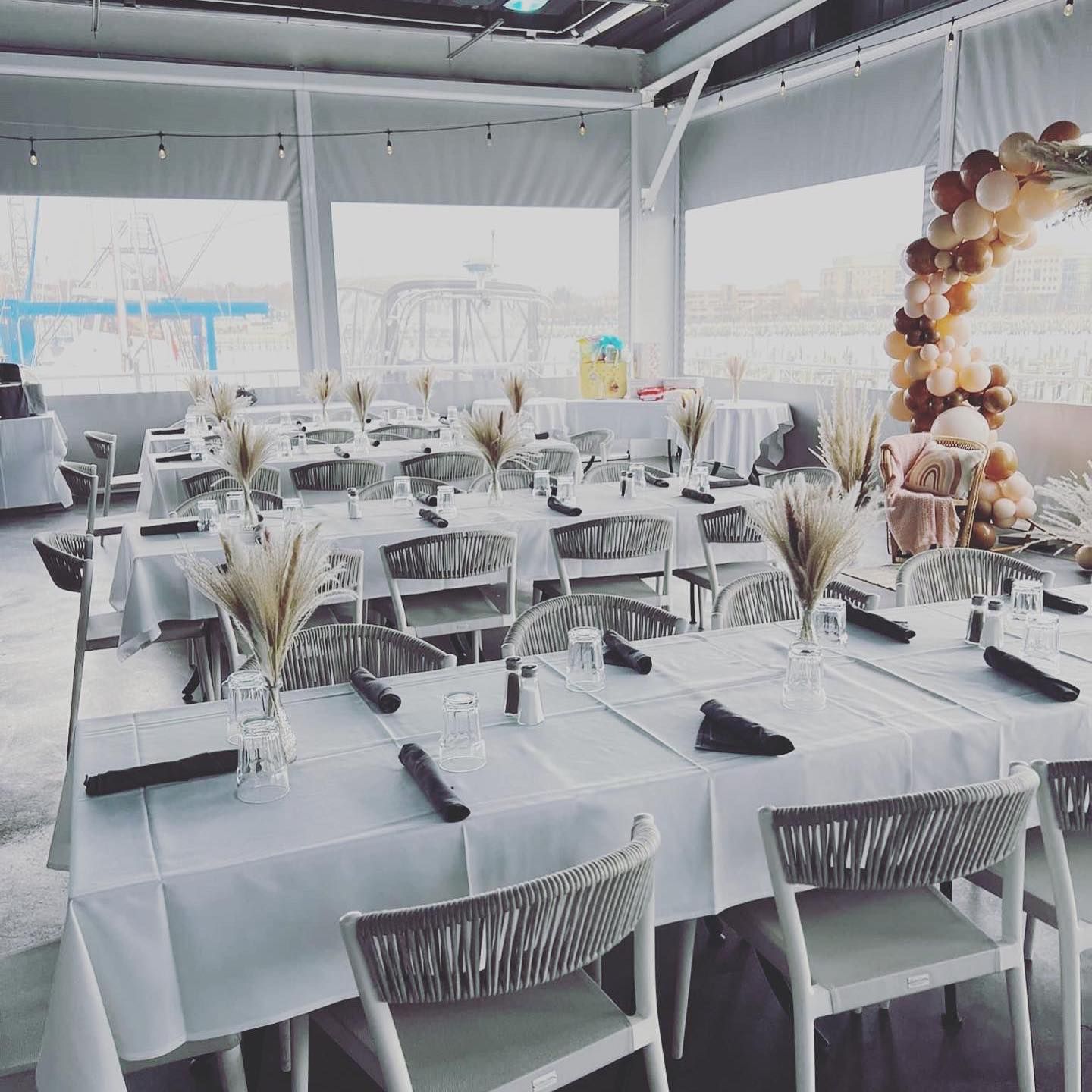Restaurant interior with decorated tables, beige and white color scheme, and balloon arch.