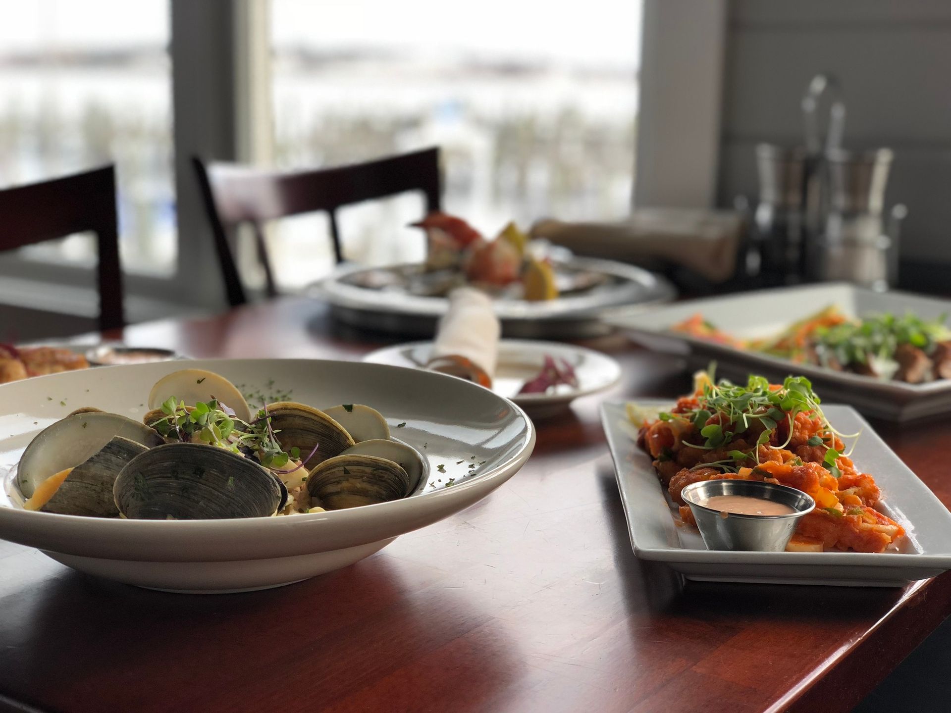 Clams, fried food, and other dishes on a table in a restaurant with a window view.