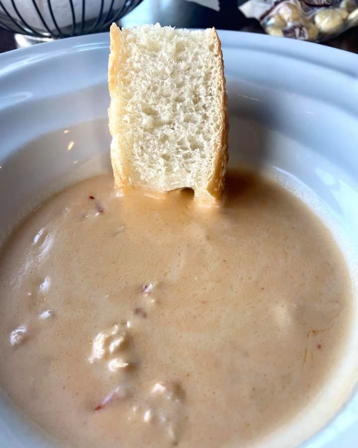 Creamy soup in a white bowl, with a large piece of bread sticking out.