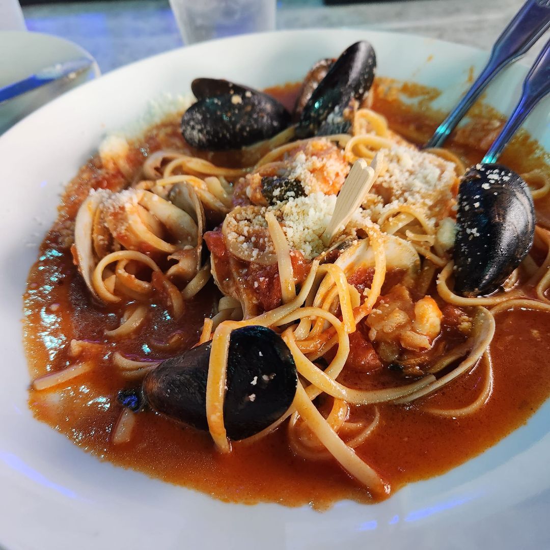Seafood pasta with mussels, clams, and parmesan cheese in a tomato sauce.