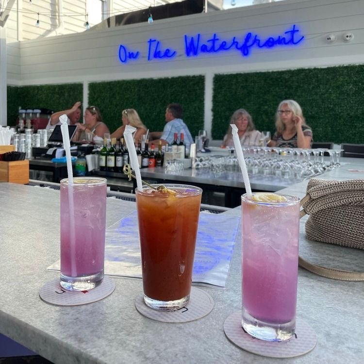 Three cocktails with people at the bar in the background.