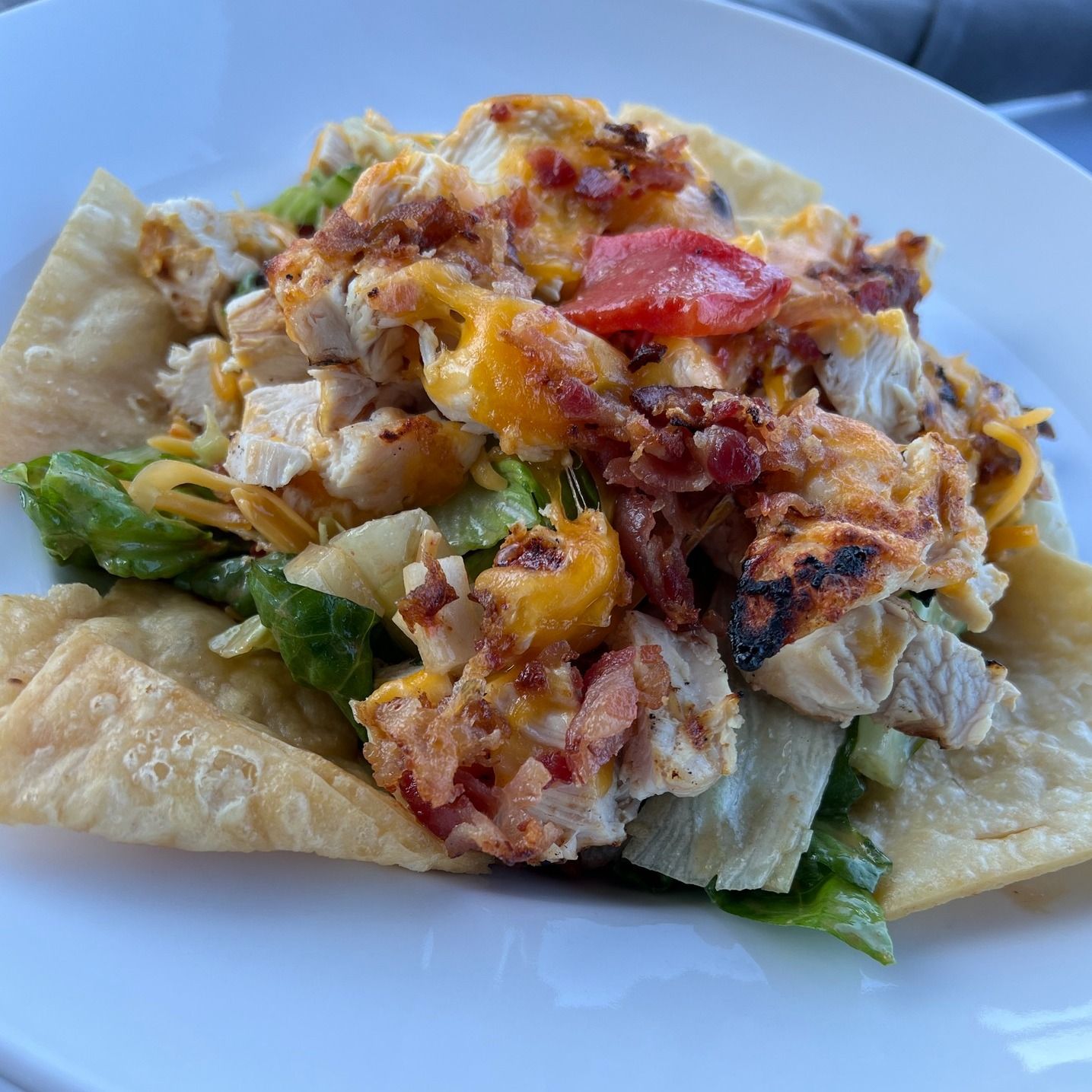 Chicken and bacon salad on a large flat tortilla shell. Includes cheese and tomato.
