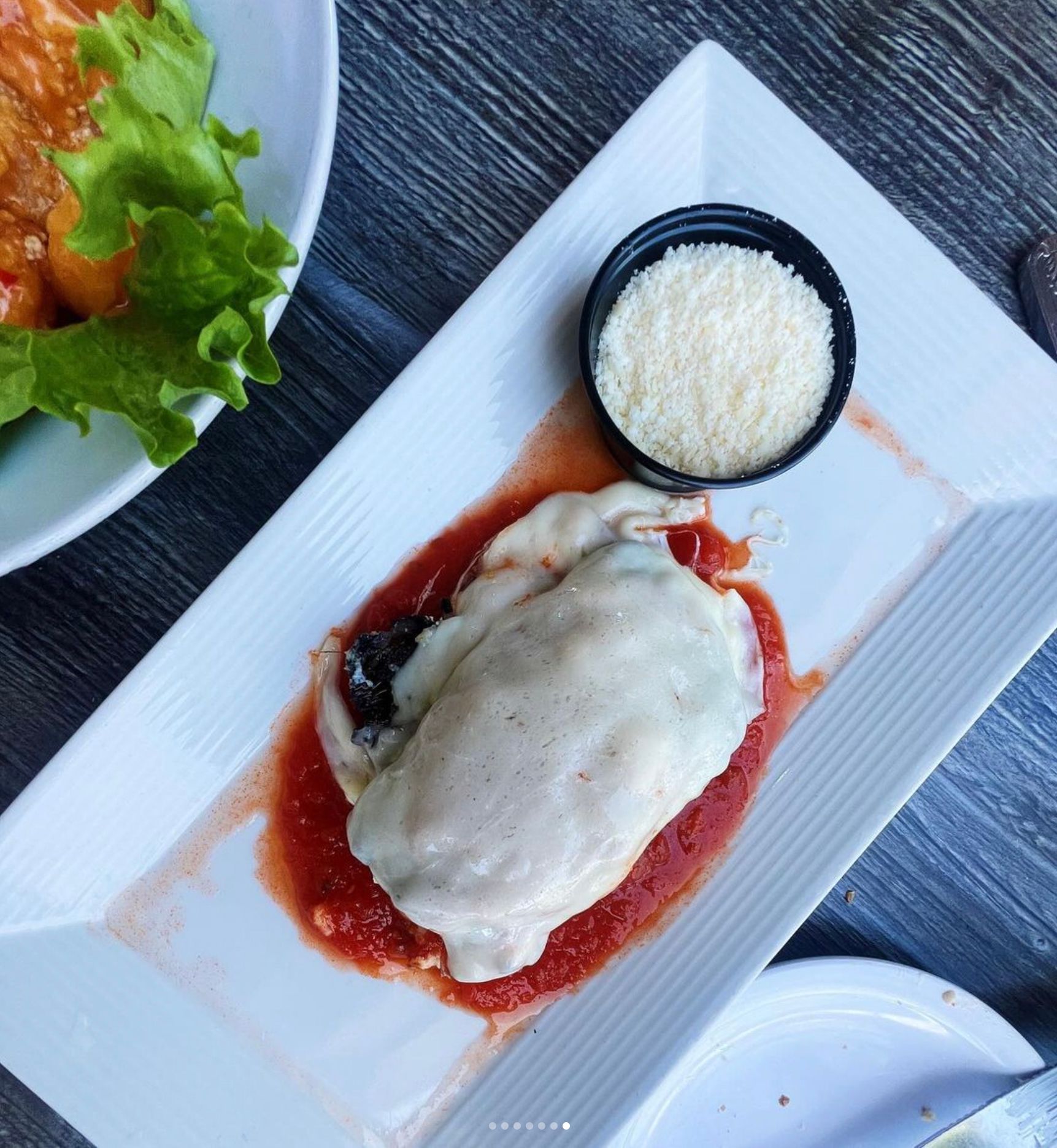 Chicken dish with tomato sauce, topped with cheese, served with grated parmesan.