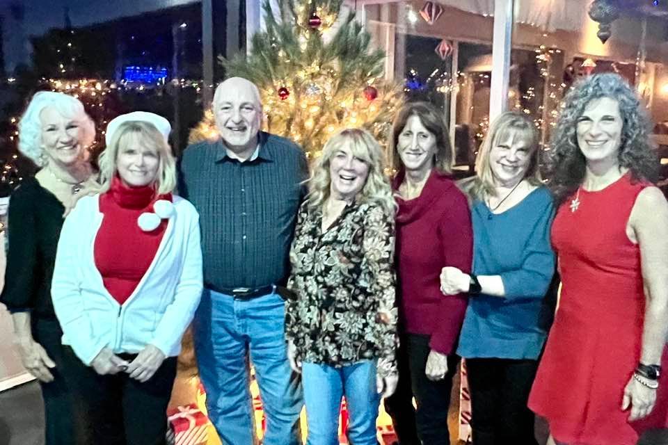 Group of people smiling in front of a Christmas tree.