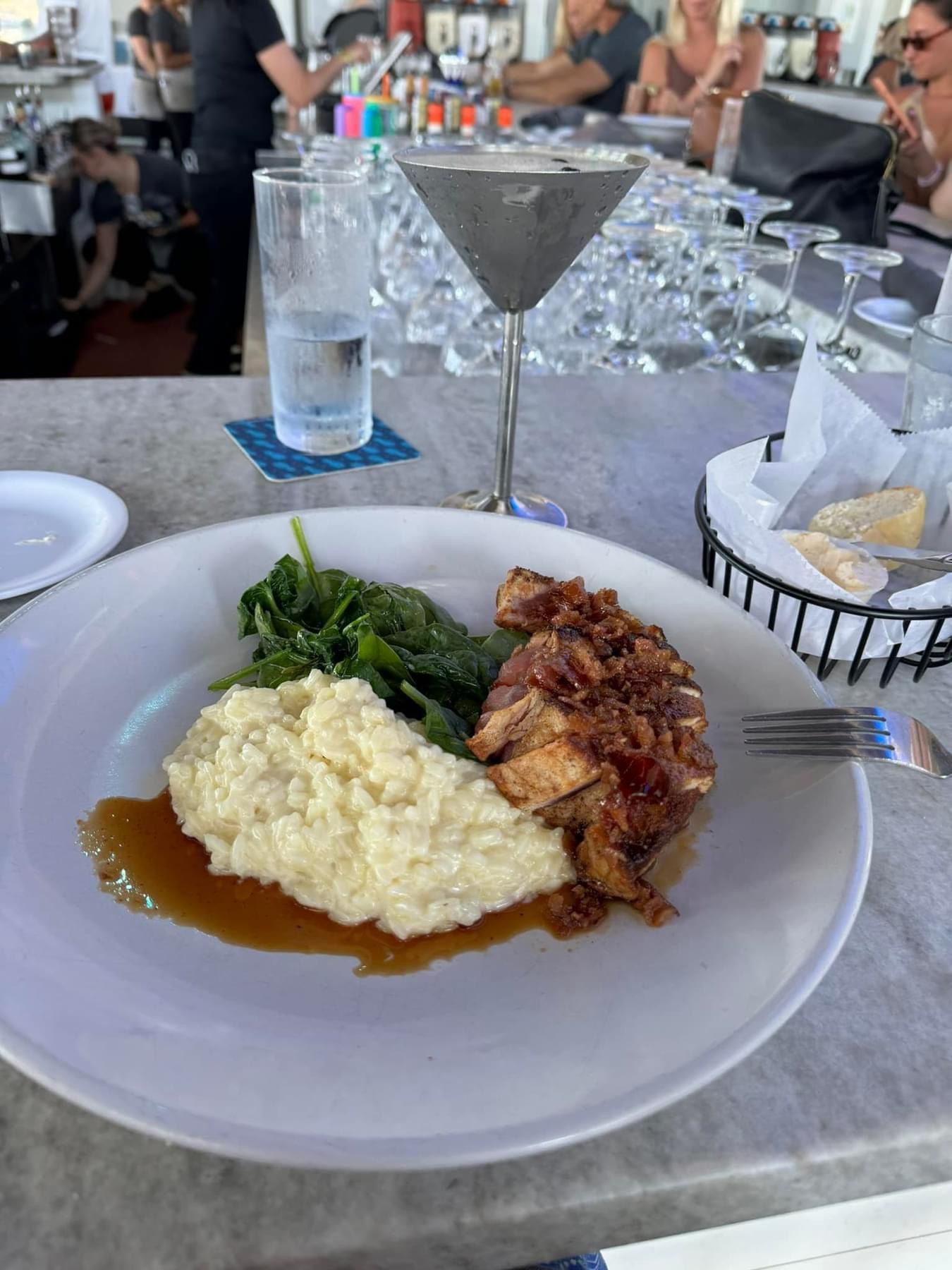 Plate of food with chicken, mashed potatoes, and spinach, next to a martini.