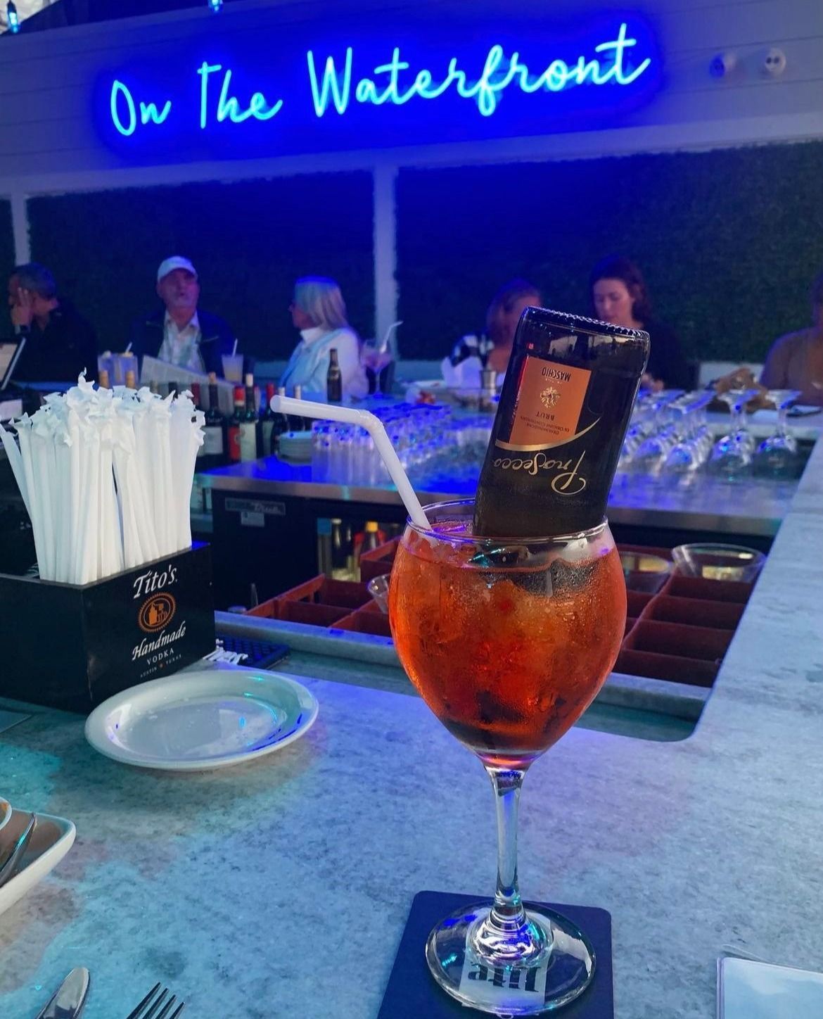 Cocktail with a small bottle in a glass at a bar.