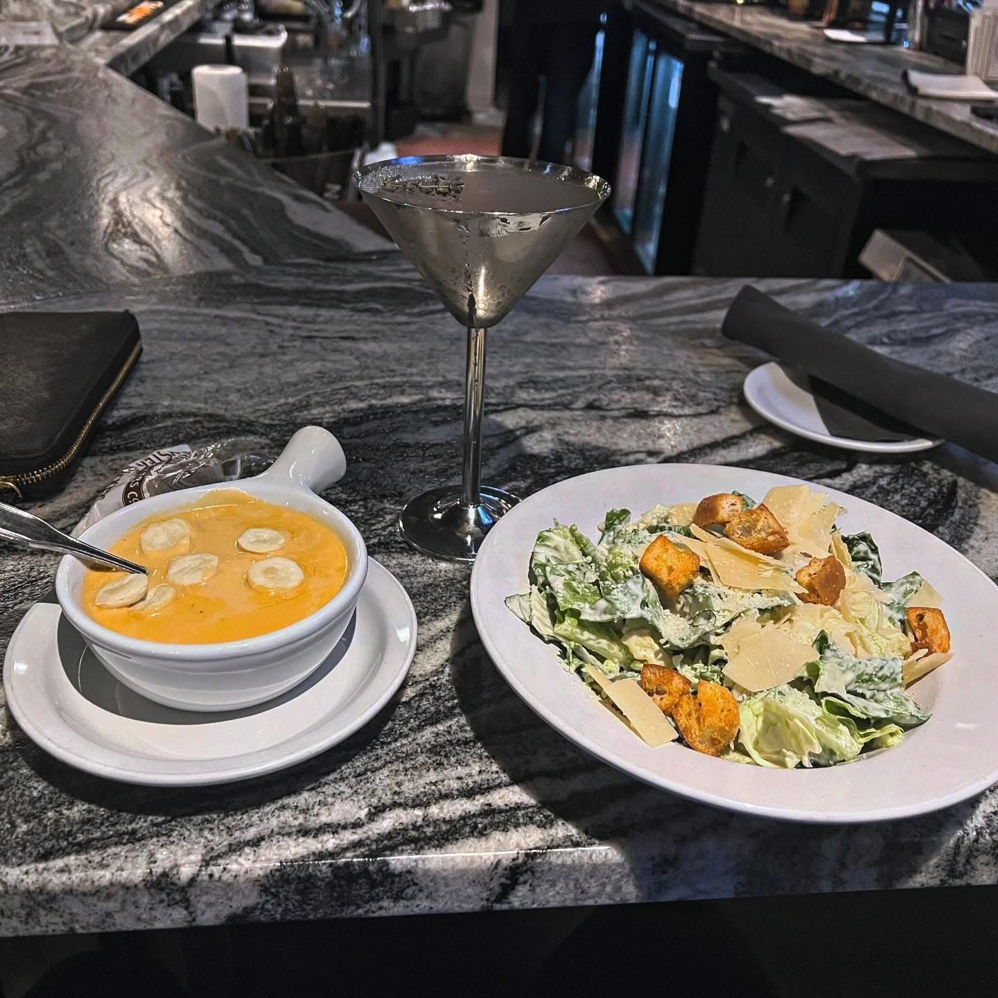 Soup, salad, and a martini on a granite bar.