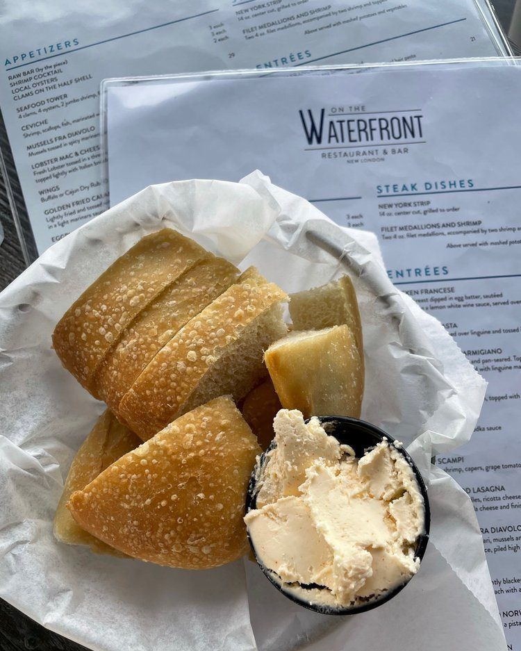 Sliced bread and butter in a basket, with a restaurant menu visible in the background.