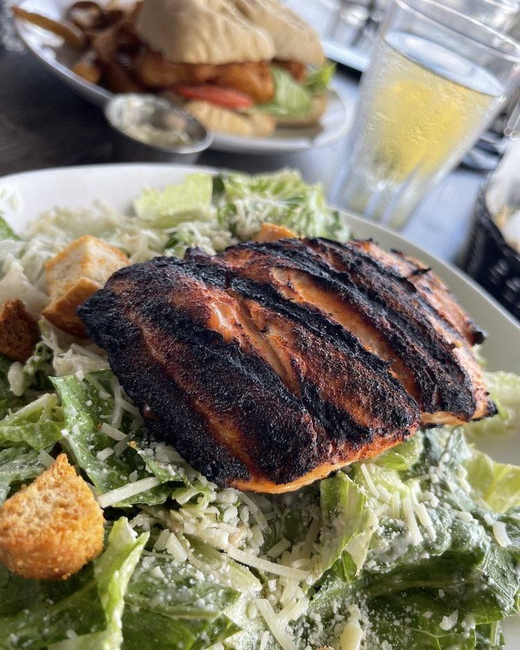 Grilled salmon atop Caesar salad with croutons.