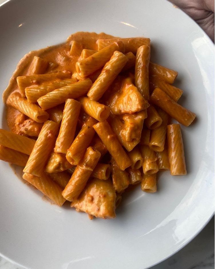 Rigatoni in creamy orange sauce, served in a white bowl.