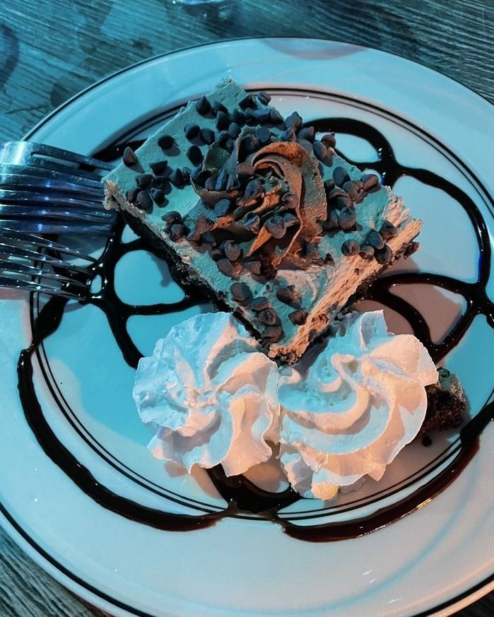Chocolate dessert with whipped cream and chocolate syrup on a white plate.