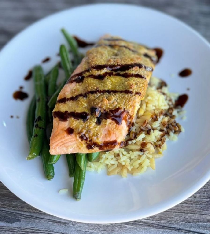 Salmon fillet with green beans and rice, drizzled with balsamic glaze.